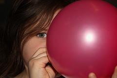 niña inflando globo rojo