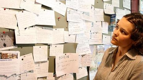 Chica en frente de una pared llena de avisos