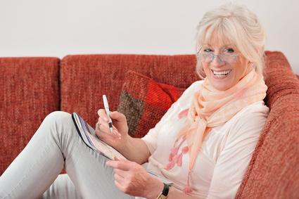 Rentnerin löst ein Kreuzworträtsel auf dem Sofa Ahorrar para la jubilación