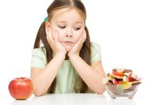 Little girl choosing between apples and sweets