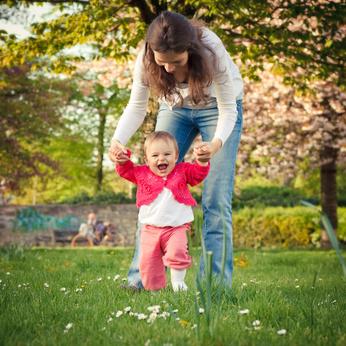 bebé de paseo con Mamá, sus primeros pasos de la mano de su madre, caminando por un jardín.