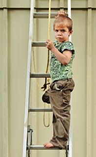 niño desafiando subido a una escalera