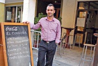 Emilio José Aguilar, en el exterior de su bar, junto al letrero que anuncia la iniciativa. j. frau