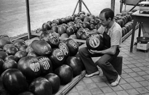 Un frutero talla escudos de equipos de fútbol en unas sandías. Madrid, 1951