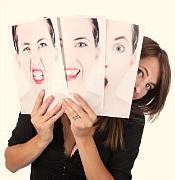 A photographer looking into a SLR camera as she points with her other hand.