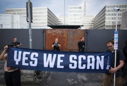 let-s-build-a-home:

YES WE SCAN
Demonstrators hold a banner...