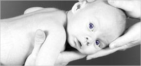 Unas manos de adulto sujetan a un recién nacido sano