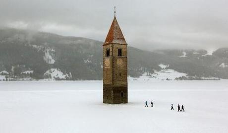 Church steeple peeking out of a frozen lake in the village of Graun