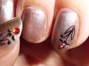 Manicura plateada piedrecita roja.