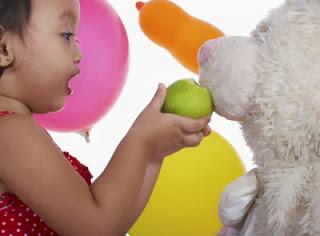 niña dando de comer a su osito