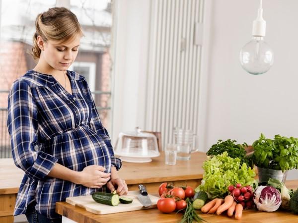 Mujer embarazada en la cocina (© REX/Cultura)