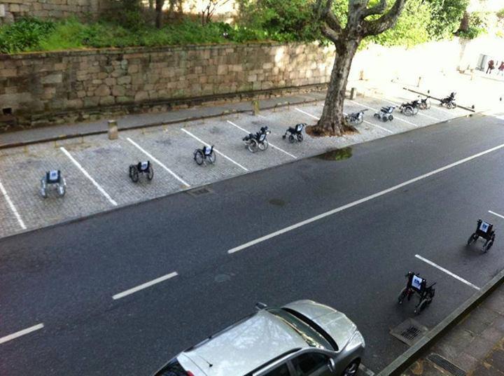 Minusválidos aparcan sus sillas de ruedas en las plazas de aparcamiento de una concurrida calle de Lisboa