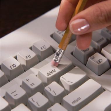 Hand holding pencil, rubbing against delete key on keyboard Hand holding pencil, rubbing against delete key on keyboard