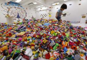 A boy plays on an artwork made out of unwanted toys at the solo exhibition of Japan artist Hiroshi Fuji, known for his creations in the theme of recycled unwanted toys and waste materials in Tokyo
