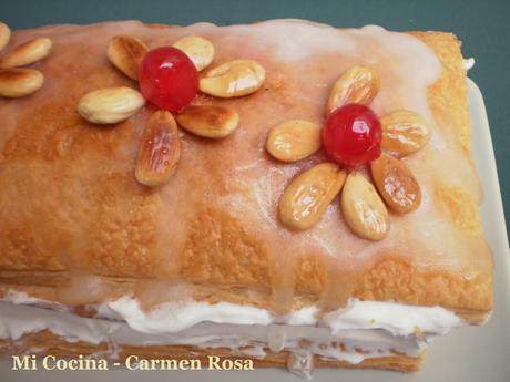 HOJALDRE GLASEADO CON AROMA DE ANIS, RELLENO DE NATA MONTADA AVAINILLADA CON FLORES DE ALMENDRAS Y GUINDAS.