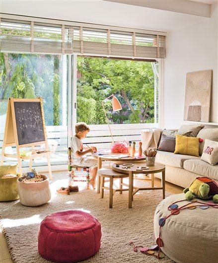 Salón con zona de juegos y niño dibujando sobre una mesa nido