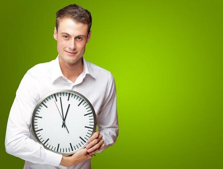 Happy Man Holding Clock In His Hand On Green Background