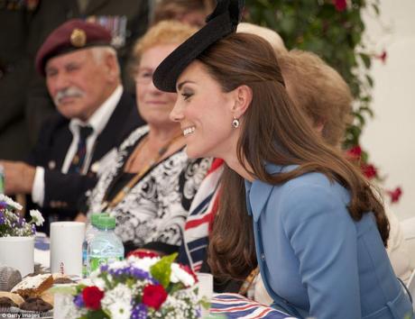 Conversation: The Duchess looked respectful in a light blue dress-coat and an elaborate black head piece as she spoke with guests