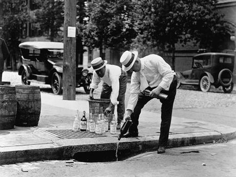 ca. 1915-1935 --- Men Pouring Whiskey into Sewer (Hombres vertiendo whiskey en una alcantarilla)--- Image by © CORBIS
