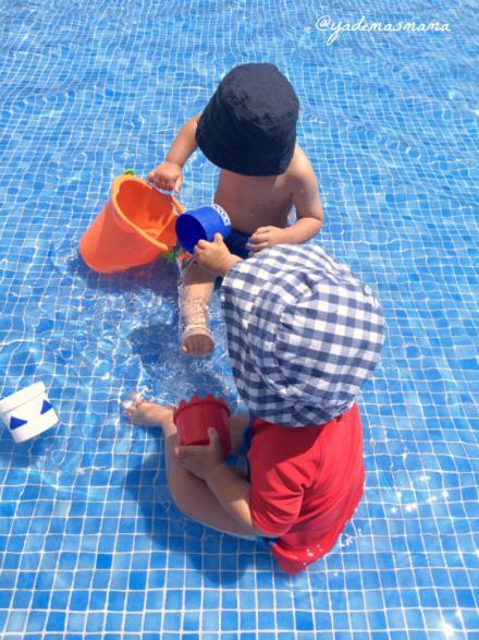 bebés jugando en la piscina con cubos de agua