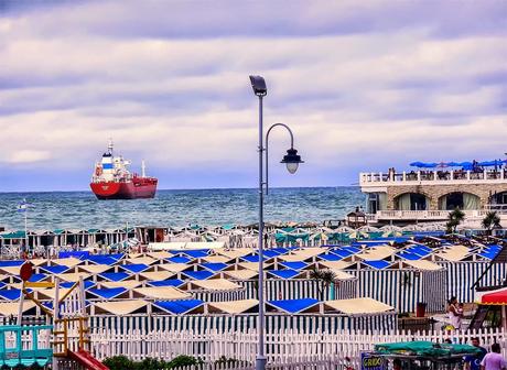 Un barco en el mar y  carpas en playa.