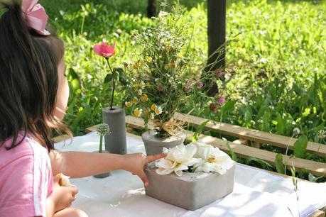 Mi niña decorando la mesa del picnic de la huerta con un palet y los diy floreros de cemento