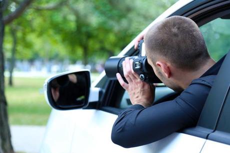 Detective privado haciendo una foto oculto en un coche
