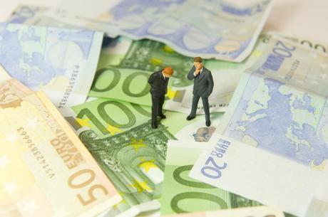 Hommes discutant sur un tapis de billet en euros