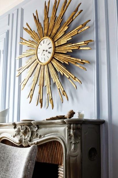 Un salón con un gran espejo sol convertido en reloj