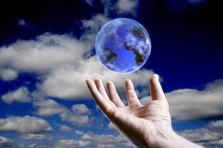 Abstract earth hoovering over an open hand with sky background