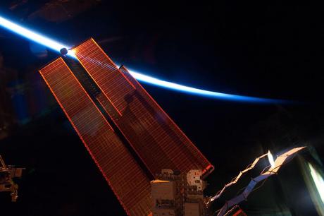 Intersecting the thin line of Earth's atmosphere, International Space Station solar array wings