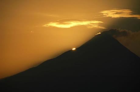 the sun's disc peeps out from the slopes of Gunung Merapi nearby is Borobudur