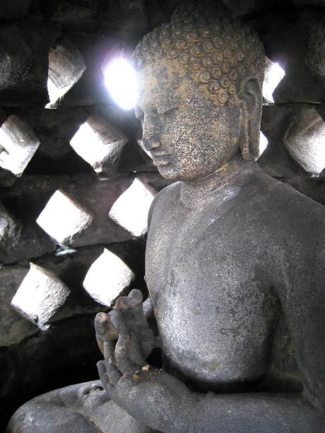 A meditative Buddha statue perform dharmachakra mudra hand gesture inside the perforated bell-shaped stupa on upper platform of Arupadhatu in Borobudur.