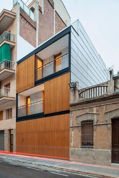 Entre dos bloques, una vivienda diseñada hacia el interior donde la madera es protagonista