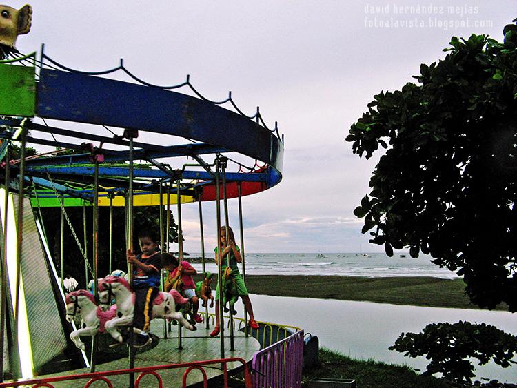 Niños montando en los caballitos a orillas del mar