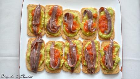 Tosta de guacamole, tomate y anchoas.