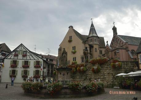 Plaza principal de Eguisheim con la fuente renacentista y la iglesia de san Pedro y san Pablo en Eguisheim