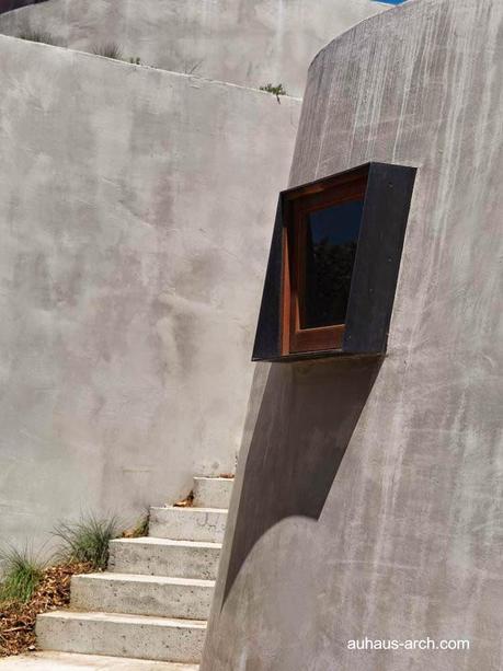 Casa orgánica rústica de concreto, madera y metal.