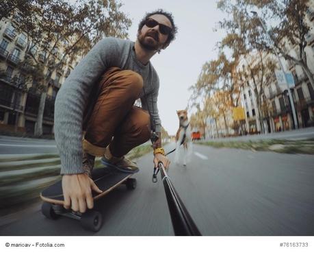 Man rides his longboard followed by his dog