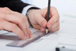 Businessman Working On Blueprint At Desk