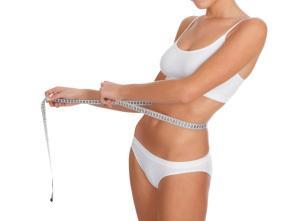 fit young woman measuring her waistline, white background