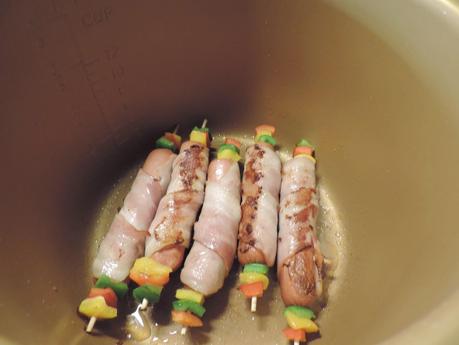 Brochetas de salchichas de pollo, bacon, pimiento y queso con arroz blanco.