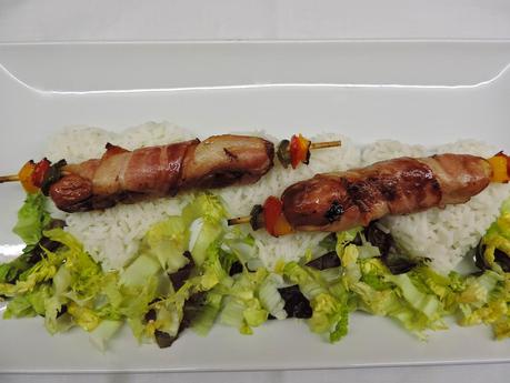 Brochetas de salchichas de pollo, bacon, pimiento y queso con arroz blanco.
