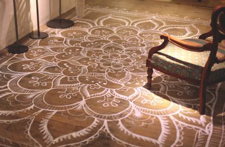 Mandala o kolam pintado sobre suelo de madera