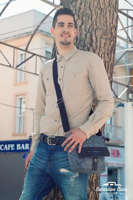chico modelo con cartera posando en Alhama de Murcia apoyado en arbol