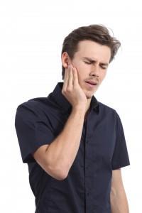 Casual man suffering toothache with hand pressing on face