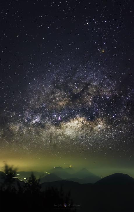 La Vía Láctea sobre un volcán en erupción