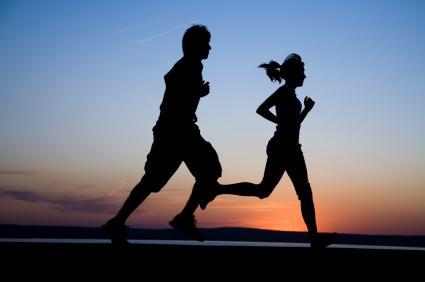 The man and the woman run together on a sunset on lake coast