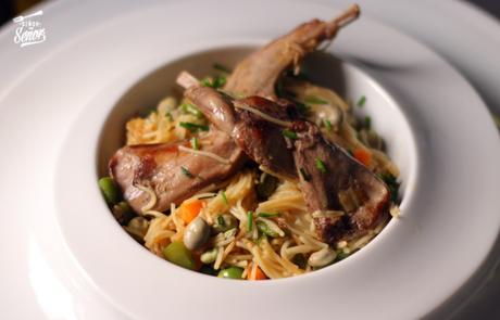 Conejo con fideos, habas y guisantes frescos
