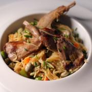 Conejo con fideos, habas y guisantes frescos